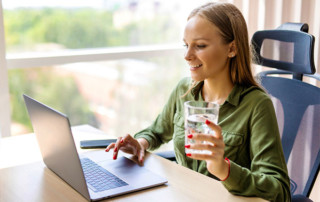 Person Holding a Glass of Water Looking at Laptop Admiring Water Utility Digital Transformation By Chateaux